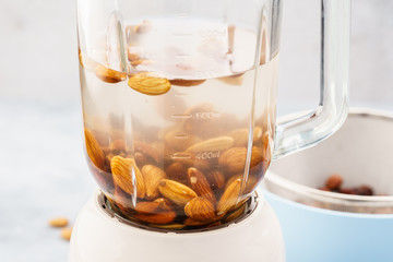 Blender and almonds soaked in water. Making vegan milk.