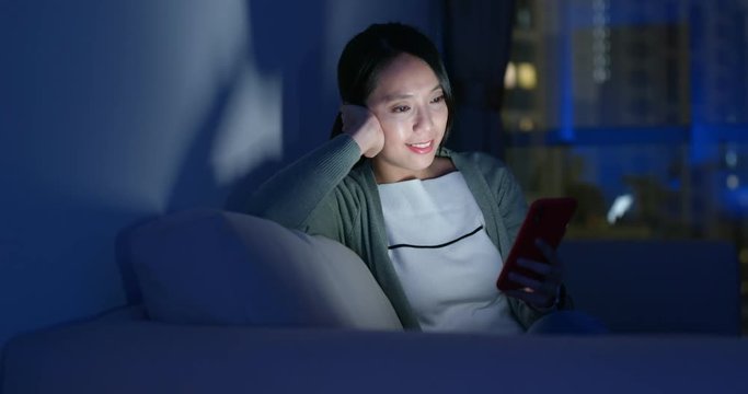 Asian woman look at cellphone and sit on couch