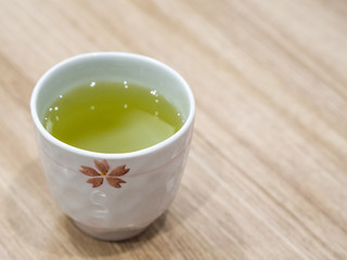 Closeup Japanese style cup of hot green tea on wooden table in the restaurant.
