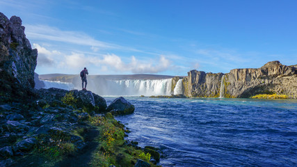 A tourist enjoy viewing and snap a photo at Godafoss the huge waterfalls. One of most famous place in Iceland - 255489847