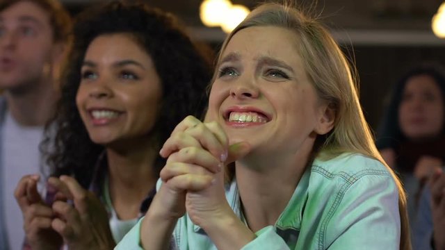 Female fans emotionally cheering for sports team victory watching football match