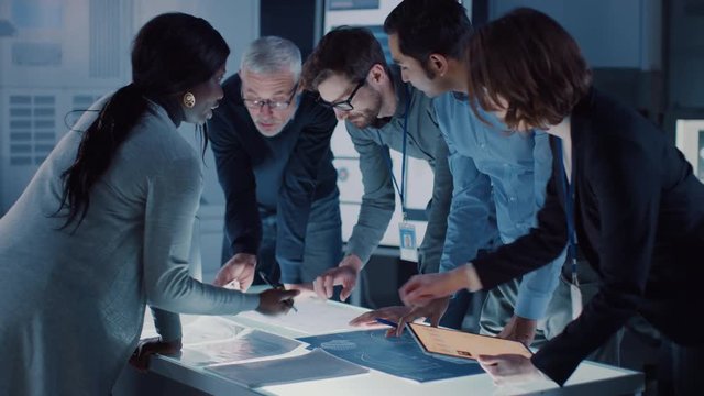 Engineers Meeting in Technology Research Laboratory: Engineers, Scientists and Developers Gathered Around Illuminated Conference Table, Talking and Finding Solution, Inspecting Engine Design.  - Powered by Adobe