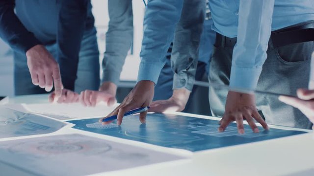 Engineer, Scientists and Developers Gathered Around Illuminated Conference Table in Technology Research Center, Talking, Finding Solution and Analysing Industrial Engine Design. Close-up Hands Shot 