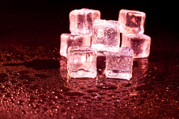 Red ice cubes on black background.