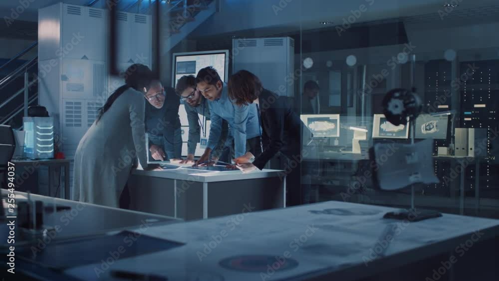 Poster Engineers Meeting in Technology Research Laboratory: Engineers, Scientists and Developers Gathered Around Illuminated Conference Table, Talking and Finding Solution, Inspecting Engine Design