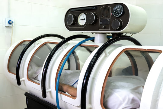 Pressure chamber. The man lies in a white altitude chamber. Equipment in a hospital or intensive care center for seriously ill people or astronauts after an overload. Close up.