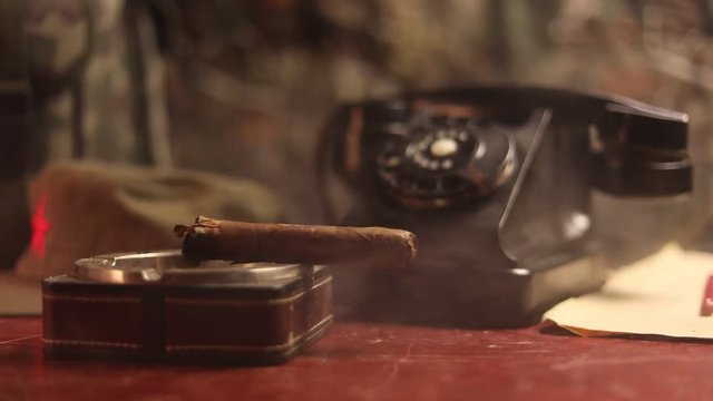 Close up of a Cuban cigar and ashtray on the wooden table. Communist dictator commander table in dark room. Army general`s work table concept. Artwork decoration