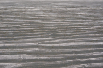 Background and texture photo of brown color sand with pile of sand from small crab and ripple shape from the sea on the beach.