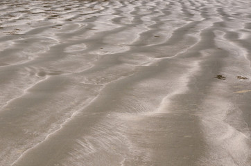 Background and texture photo of brown color sand with pile of sand from small crab and ripple shape from the sea on the beach.