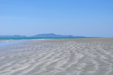 Fototapeta na wymiar Photo of the brown beach with sea and mountain and blue sky.