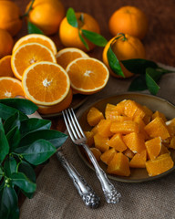 Oranges sliced and  orange leaves on a kitchen table with rustic background