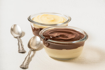 Vanilla and chocolate pudding in a glass bowls on white background, copy space. Tasty and low-calorie breakfast