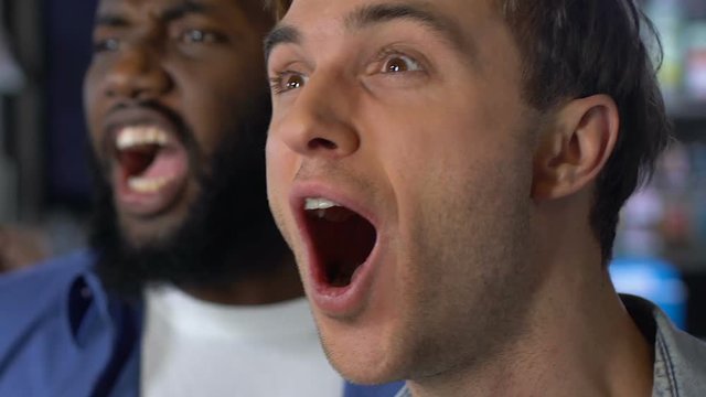 Multiracial men emotionally supporting favorite sports team, premier league