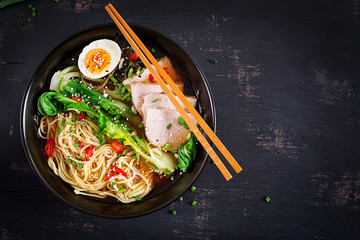 Miso Ramen Asian noodles with egg, pork and pak choi cabbage in bowl on dark background. Japanese...