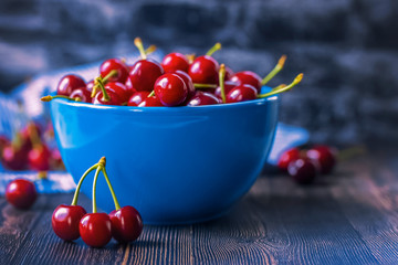 cherries in a blue bowl and on the table close-up. background with cherries. cherres close-up.