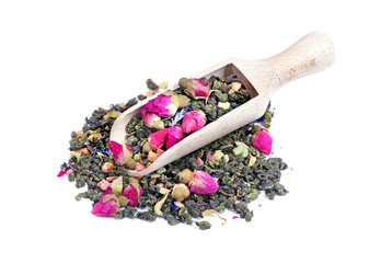 green tea in a wooden scoop isolated on a white. green tea with flowers and fruit pieces. blend tea
