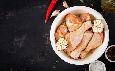 Raw uncooked marinated chicken legs, drumsticks for cooking on dark table. Asian cuisine. Top view