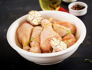 Raw uncooked marinated chicken legs, drumsticks for cooking on dark table. Asian cuisine.
