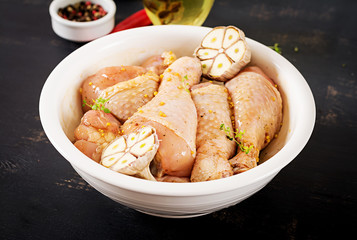 Raw uncooked marinated chicken legs, drumsticks for cooking on dark table. Asian cuisine.