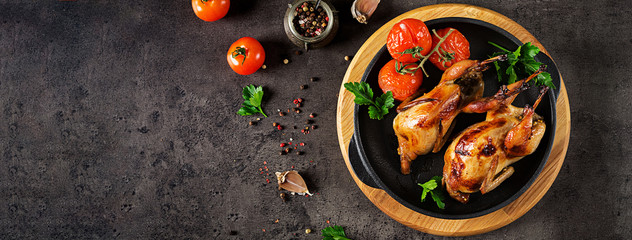 Baked quails in pan on a dark background. Top view. Banner. Free space for your text.