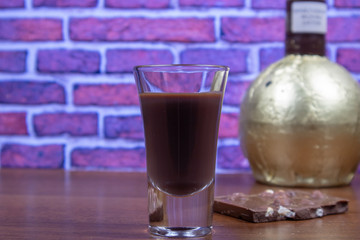 Chocolate liqueur in a shot glass and a piece of chocolate