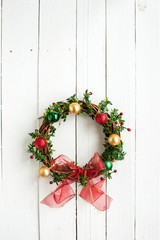 Flat lay Christmas wreath on white wooden wall or door. Text space image.