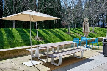 picnic table under a tan umbrella in a corporate office campus