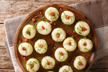 Homemade round potato dumplings with bacon and green onions close-up on a plate. horizontal top view