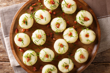 Polish authentic kluski potato dumplings with bacon and green onions close-up on a plate. Horizontal top view