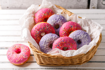 Concept of cooking, baking and food - close-up. Pink and purple donuts in a wicker basket in the shape of a heart. Trend colors.