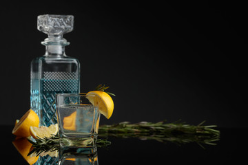 Cocktail gin , tonic with slices of lemon and a sprig of rosemary.