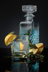 Cocktail gin , tonic with slices of lemon and a sprig rosemary.
