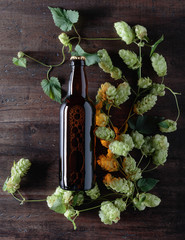 Bottle of beer and hops on a old wooden background.