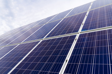 Solar cell photovoltaic panels at energy production plant with blue cloudy sky in the background