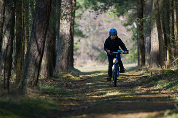 Obraz premium Boy with blue helmet rides a bicycle in forest