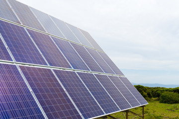 Solar cell photovoltaic panels at energy production plant with blue cloudy sky in the background