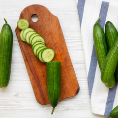Fresh raw green cucumbers over white wooden surface, overhead view. Flat lay, from above, top view.