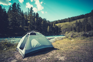 Camping tent in campground at national park. Tourists camped in the woods on the shore of the lake on the hillside. View of tent on meadow in forest. Camping background.