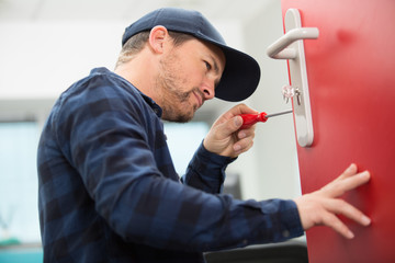 man installing screws in wooden door