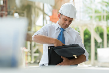 man in suit and construction helmet looking for paper
