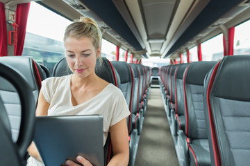 businesswoman traveling by coach using a tablet computer