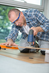 man cutting laminate board with jigsaw