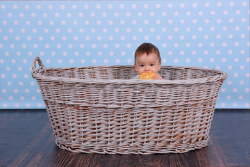 A tiny child eats a dry bun in a basket woven from a wicker tree.