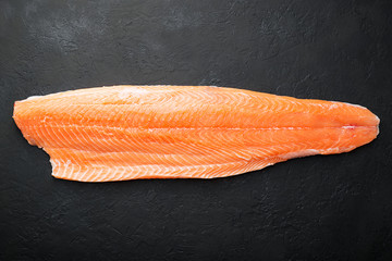 Fresh raw salmon fish steak on dark stone background.