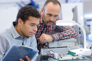 young male electrical engineering student observing microchip