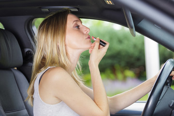 Fototapeta na wymiar woman putting on lipstick in a car
