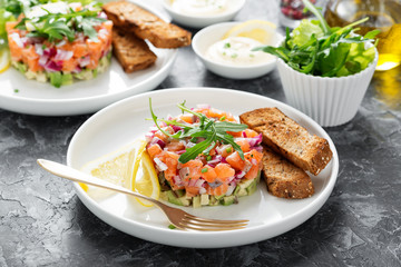 Salmon tartare with red onion, avocado, arugula and bread toast.