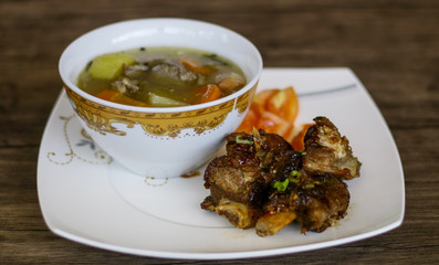 Grilled ribs, soup and chili sauce on wood background. 