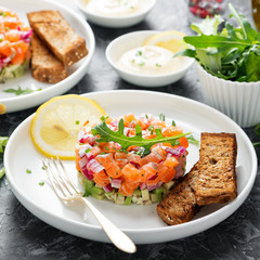 Salmon tartare with red onion, avocado, arugula and bread toast.