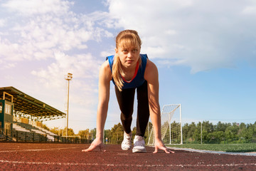 Athletic teenage girl in start position on track. Concept of moving forward.